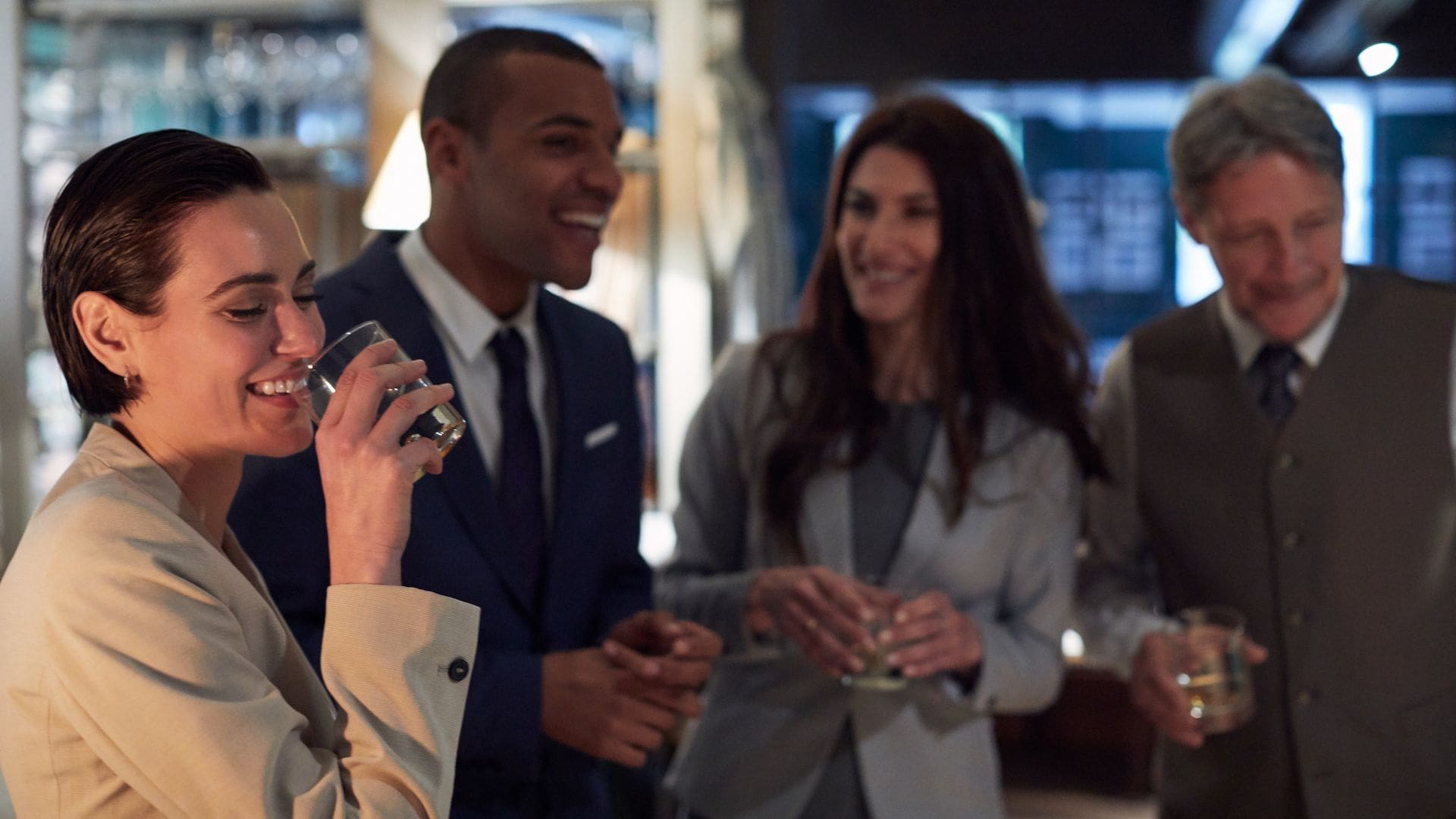 Group of professionally dressed guests holding cocktails and socializing during a hosted open bar at a private event.