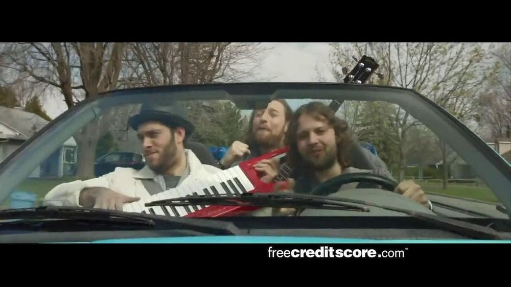 Three friends riding in a convertible singing with a keyboard, referencing the nostalgic Free Credit Report commercial about “free” services.