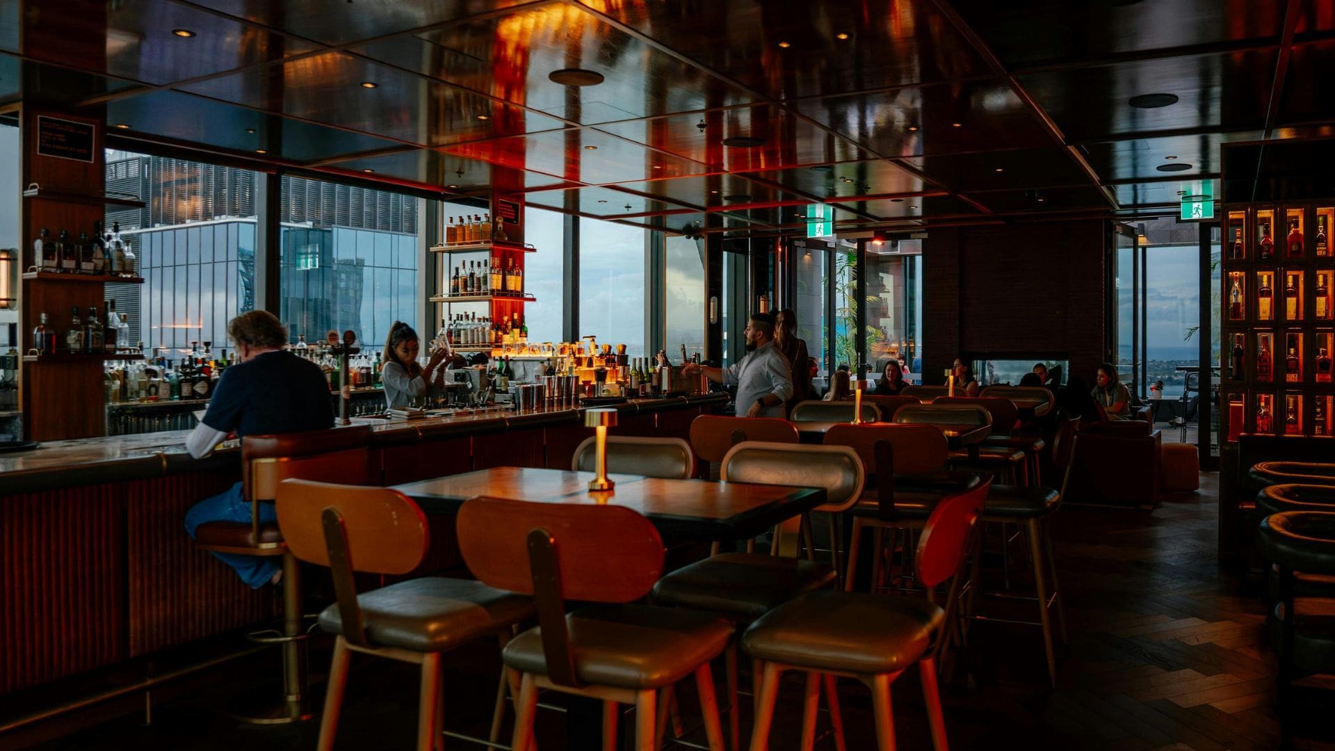 Upscale bar and lounge with floor-to-ceiling city views and warm ambient lighting set up for a private event