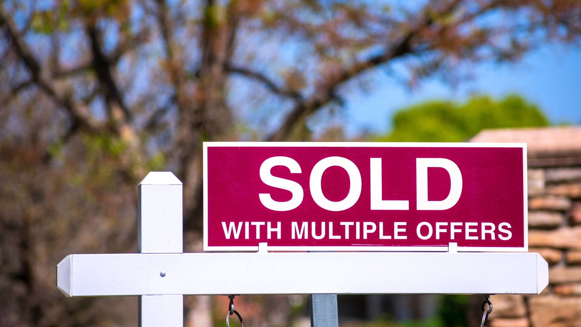 Real estate sold sign with multiple offers in a suburban yard, used as a visual analogy for event venue sourcing