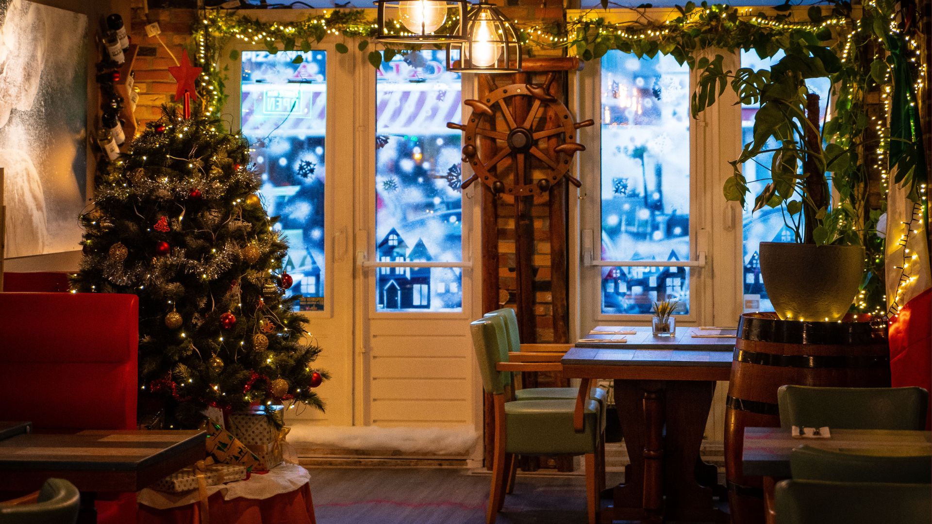 Cozy restaurant dining room decorated for the holidays with a Christmas tree and festive lights